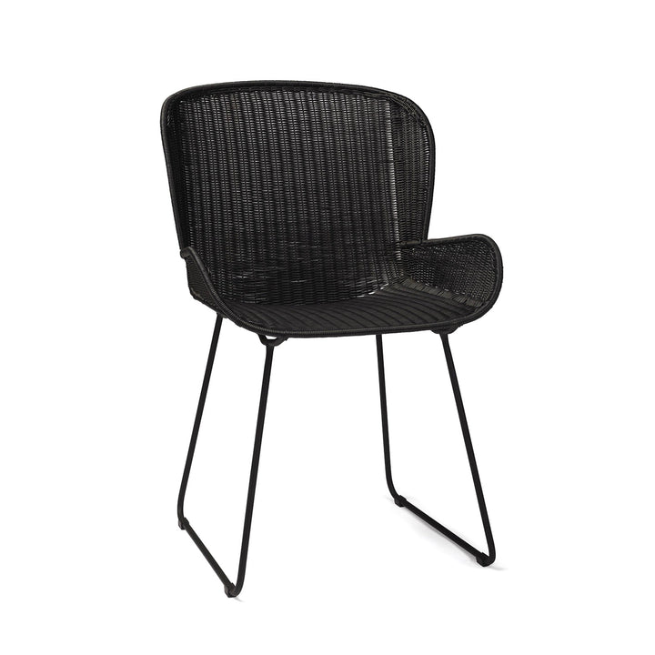 A black wicker chair with curved armrests sits on a pair of sleek metal legs, isolated against a plain white background.