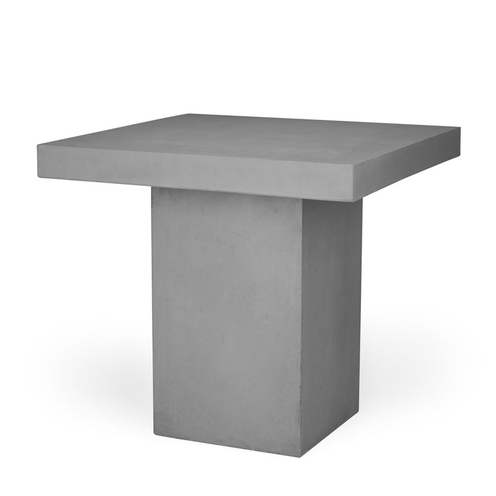 A square, solid, gray concrete table with a flat top and block-like base, standing in a well-lit, featureless space.