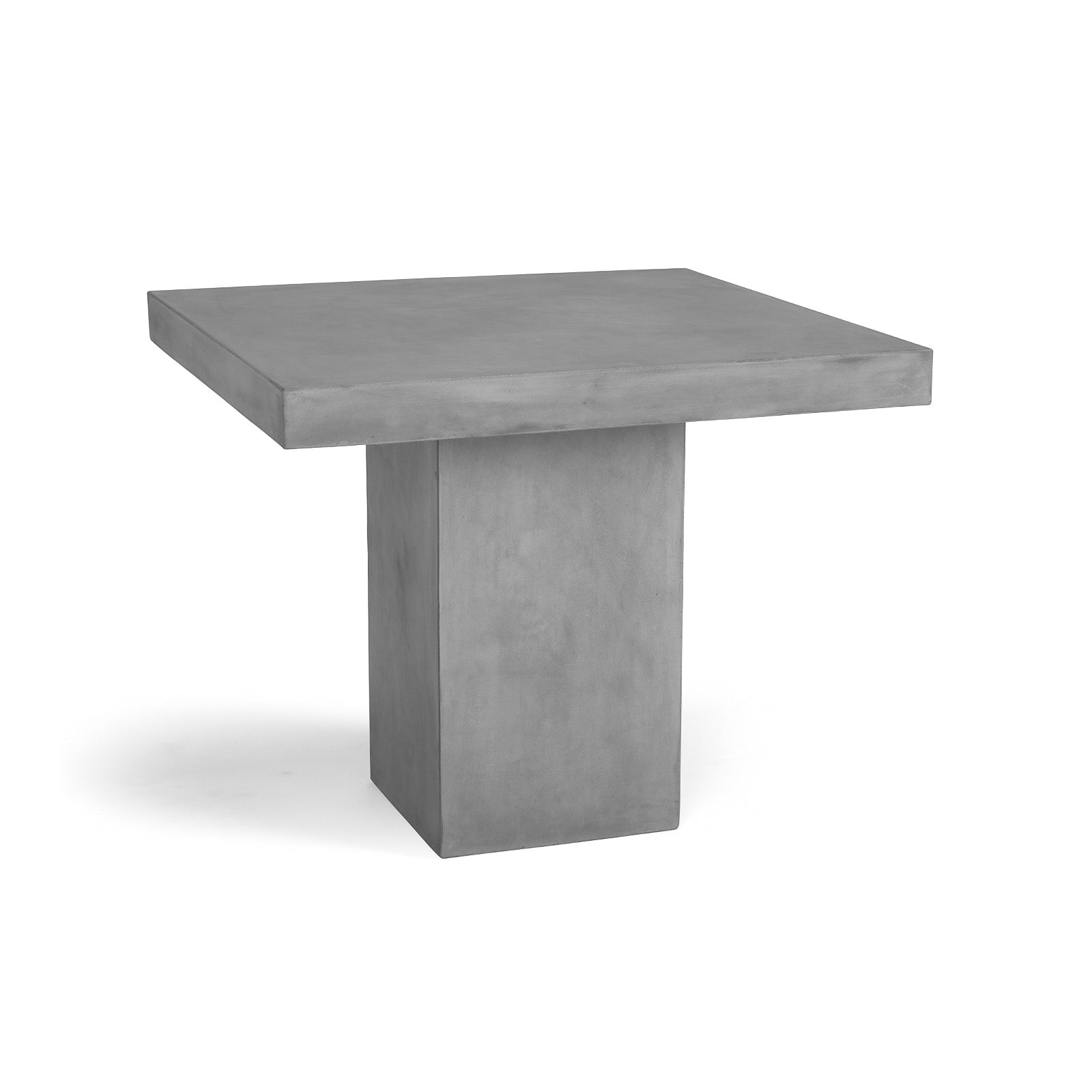 A square, gray concrete table with a solid rectangular base stands on a plain white background, suggesting a minimalist and modern design.