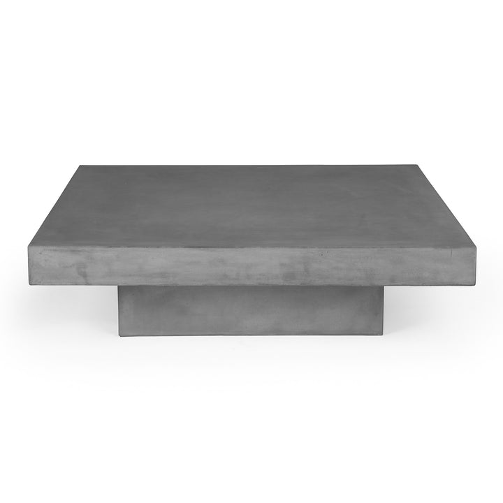 A rectangular, flat, concrete table sits on a cylindrical base against a plain white background, emphasizing its minimalist design and solid structure.