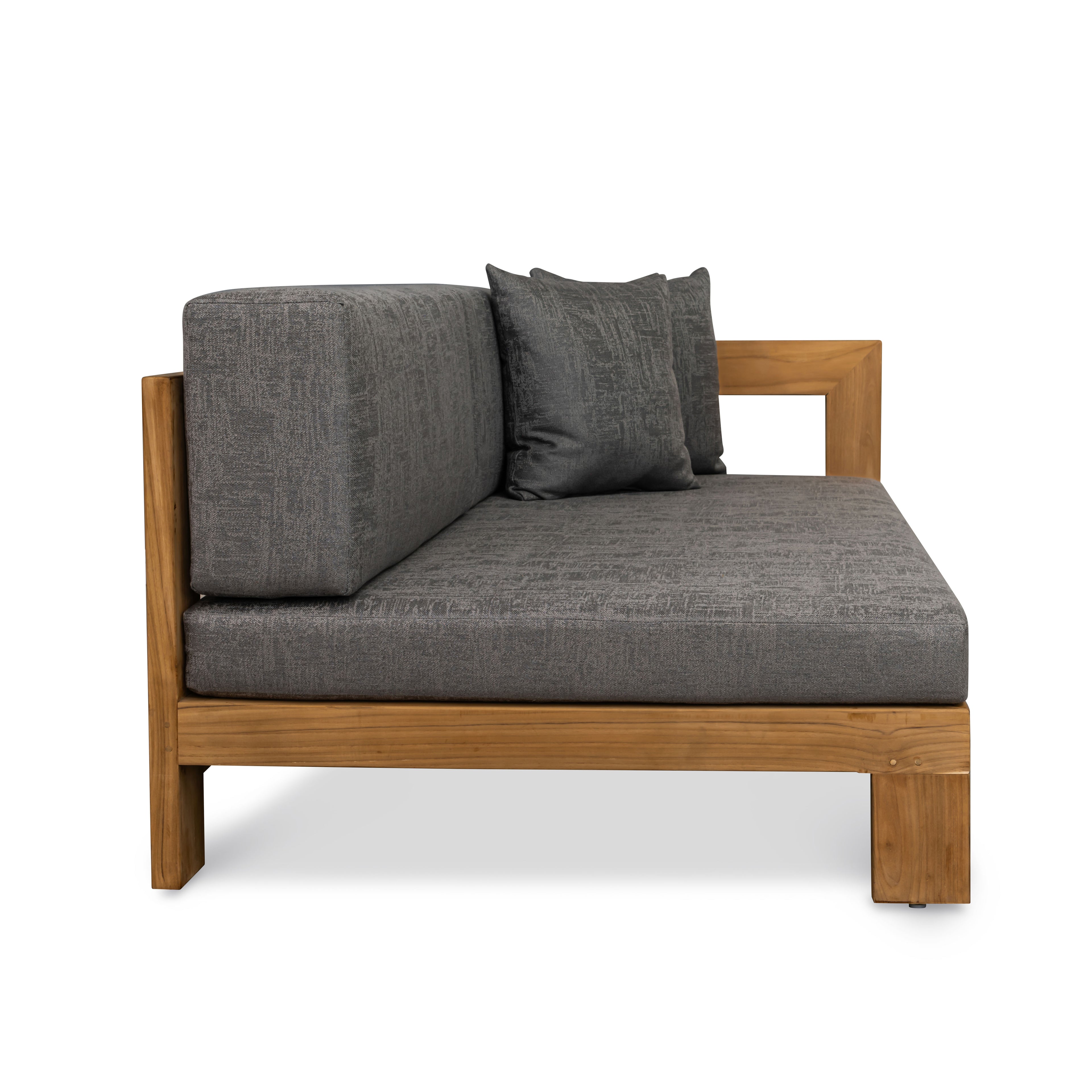 A gray cushioned daybed with two back pillows sits on a wooden frame against a white background, showing clean lines and a minimalist design.