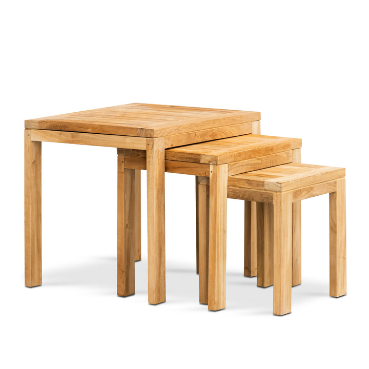 A set of three nested wooden tables, progressively reducing in size, are stacked together. They feature a simple, square design with a natural wood finish, placed against a plain background.