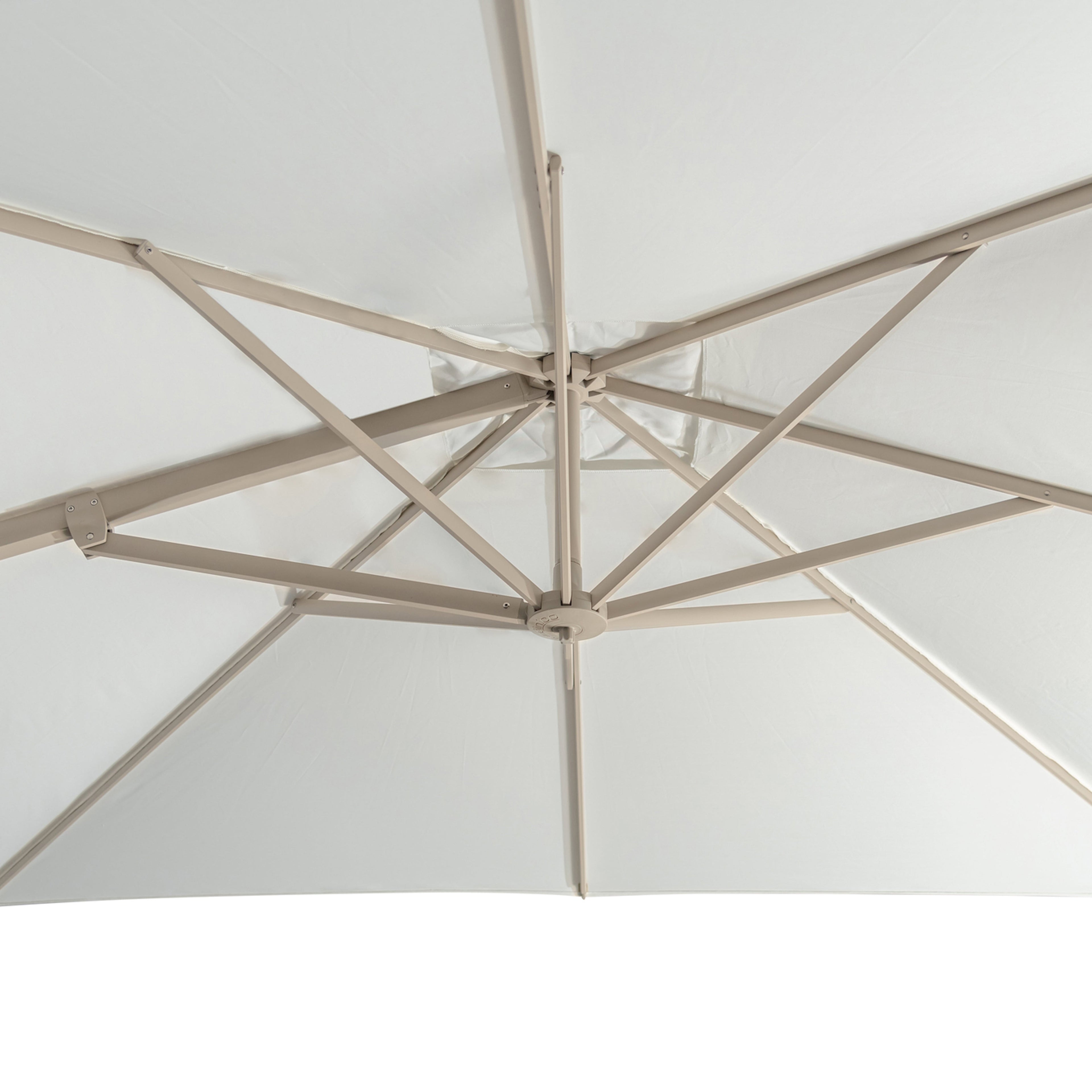 An off-white patio umbrella viewed from below, showing the metal support ribs and central hub, set against a plain background.