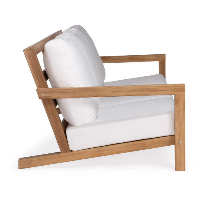 A wooden armchair features white cushions. The chair has an angled backrest and seat, creating a comfortable seating design suitable for indoor or outdoor use.