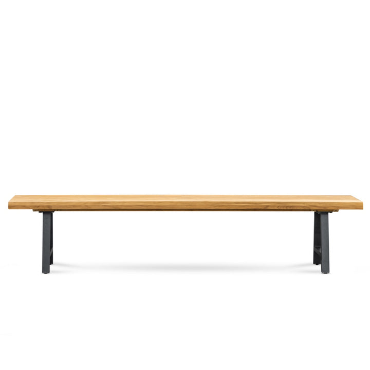 A wooden bench with a flat, smooth seat rests on sturdy metal legs, placed against a plain white background.