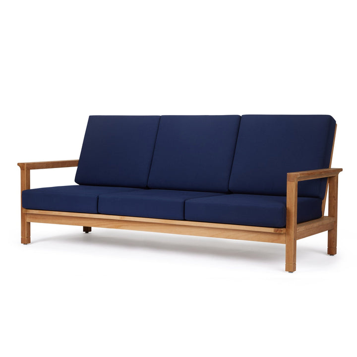 A wooden-framed sofa with blue cushions is stationary against a plain white background, emphasizing its minimalist design and focus on comfort.