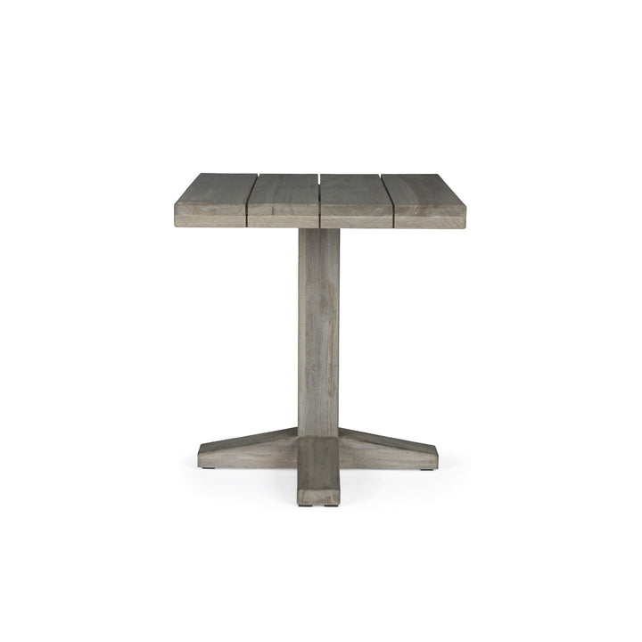 A square wooden table stands on a single pedestal with a cross-shaped base, set against a plain white background. There are no additional objects or text present.